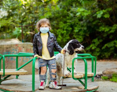 Covid-19 salgını yüzünden karantina sırasında sağlık maskesi takan, parkta köpek gezdiren havalı bir kız.