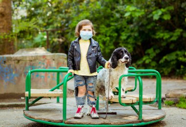 Covid-19 salgını yüzünden karantina sırasında sağlık maskesi takan, parkta köpek gezdiren havalı bir kız.