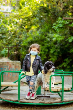 Covid-19 salgını yüzünden karantina sırasında sağlık maskesi takan, parkta köpek gezdiren havalı bir kız.