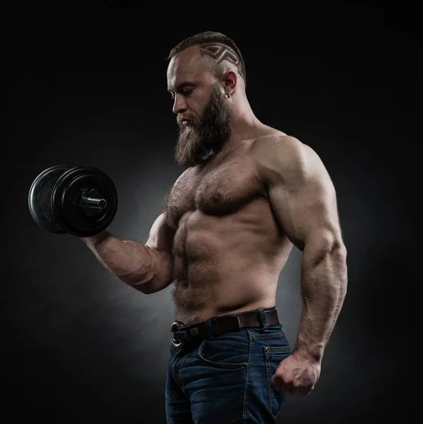Power athletic bearded man in training pumping up muscles with d — Stock Photo, Image