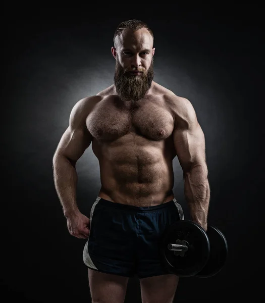 Power athletic bearded man in training pumping up muscles with d — Stock Photo, Image