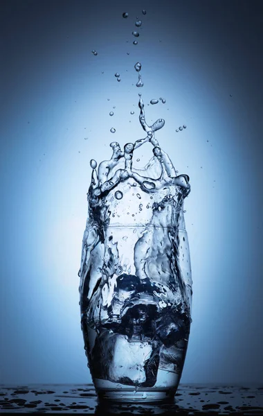 Salpicadura de agua en vidrio con cubitos de hielo —  Fotos de Stock