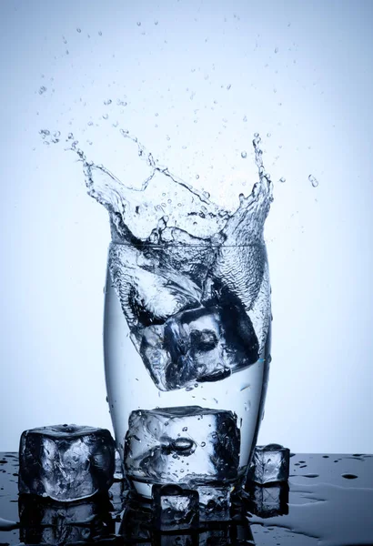 Брызги воды в стекле с кубиками льда — стоковое фото
