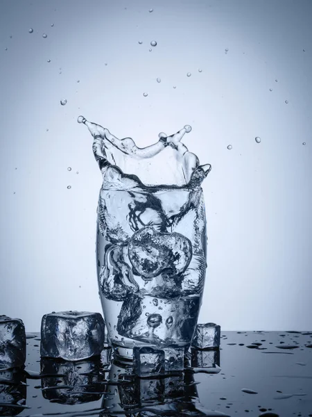 Rozprysk wody w szkle z kostkami lodu — Zdjęcie stockowe