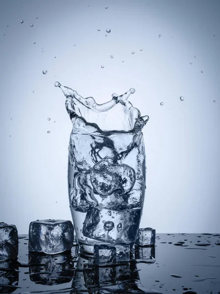 Water splash in glass with ice cubes — Stock Photo, Image