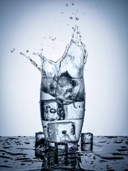 Salpicadura de agua en vidrio con cubitos de hielo —  Fotos de Stock