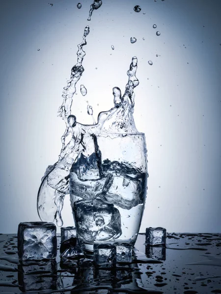 Water splash in glass with ice cubes — Stock Photo, Image