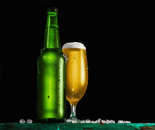 Fles en glas bier op de houten tafel op zwarte achtergrond. — Stockfoto