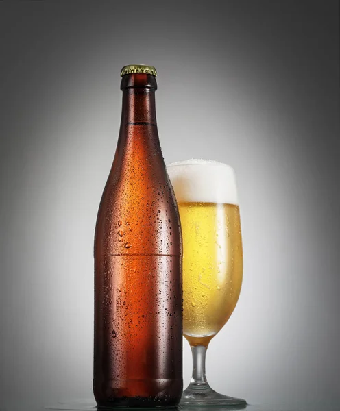 Fles en glas bier op de houten tafel over grijs pagina — Stockfoto