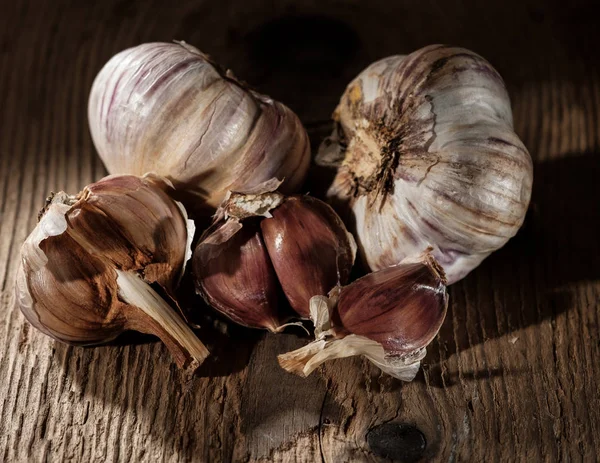 Garlic bulbs and garlic cloves on wooden background.
