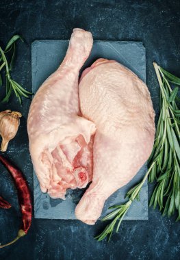 Siyah taş plaka üzerinde çiğ tavuk uyluk.