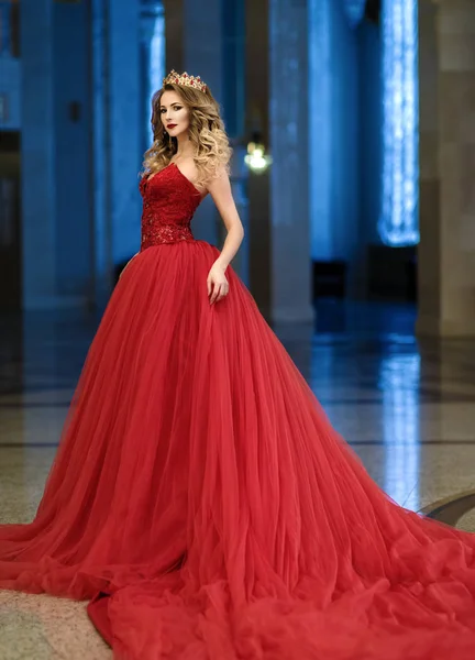 Beautiful woman in a red long dress and a golden crown in the gr — Stock Photo, Image