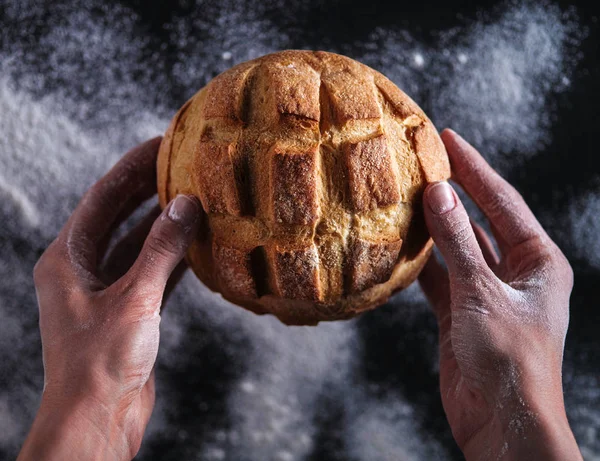 Руки пекаря держат свежий хлеб — стоковое фото