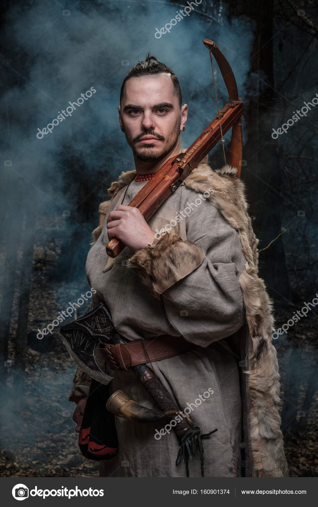 Viking warrior with crossbow and ax in the woods. — Stock Photo