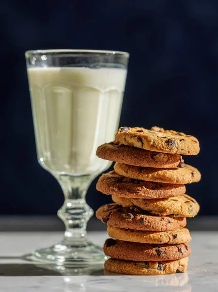 Vaso de leche y galletas en mesa de piedra con fondo de pared oscura —  Fotos de Stock