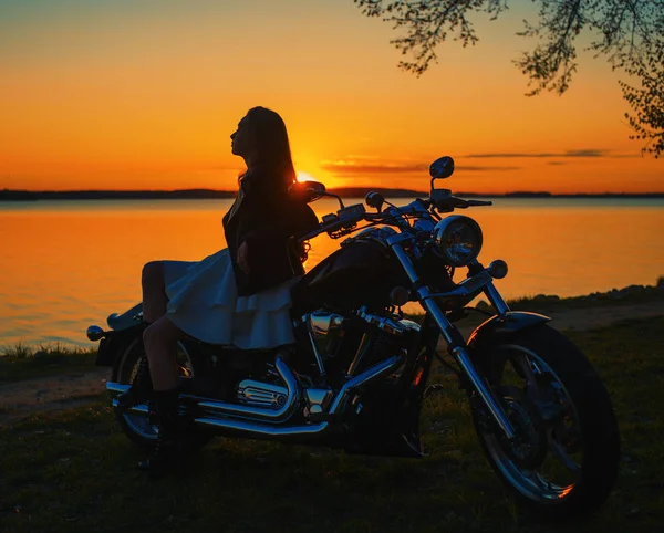 Bir motosiklet üzerinde oturan genç kız. Günbatımı. — Stok fotoğraf