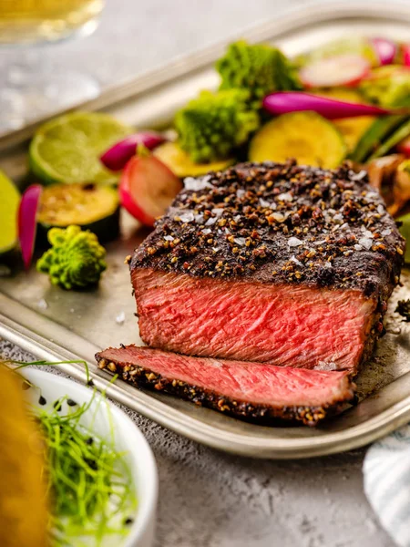 Een gegrilde peper steak gegarneerd met citroen, ui en verse kruiden — Stockfoto