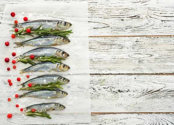 Arenque cru fresco do Báltico do peixe na tabela de madeira branca com ervas frescas e cowberry — Fotografia de Stock