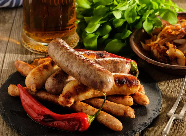 Grilled sausages and stewed cabbage with a mug of beer on a wood — Stock Photo, Image