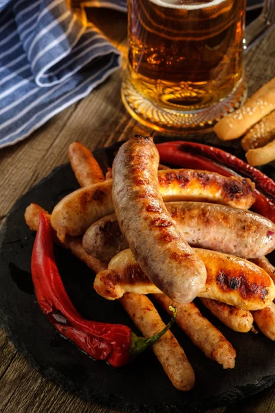 Grilled sausages with a glass of beer on a wooden table. Rustic — Stock Photo, Image
