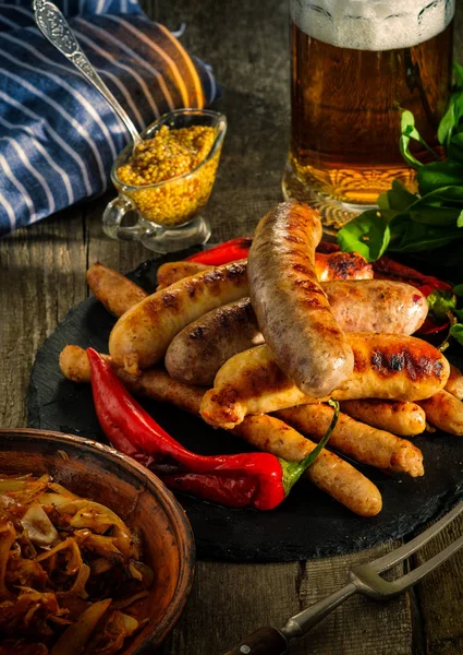 Grilled sausages and stewed cabbage with a mug of beer on a wood — Stock Image Grilled sausages and stewed cabbage with a mug of beer on a wood Stock Image