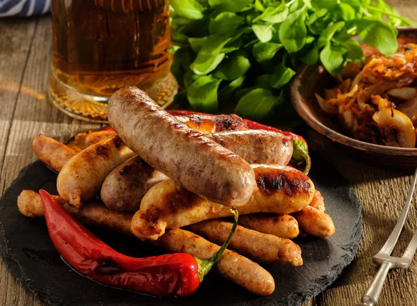 Grilled sausages and stewed cabbage with a mug of beer on a wood — Stock Image Grilled sausages and stewed cabbage with a mug of beer on a wood Stock Image