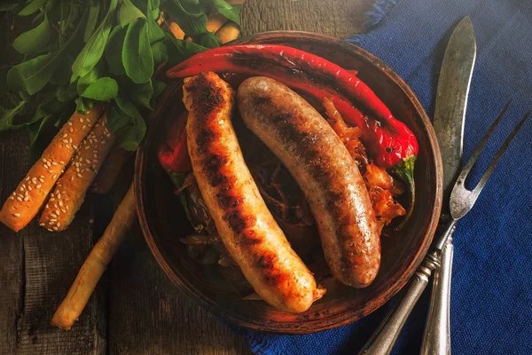 Grilled sausages and stewed cabbage on a wooden table. — Stock Image Grilled sausages and stewed cabbage on a wooden table. Stock Image