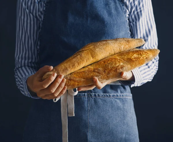 Baker holding freshly baked baguettes. Toned image