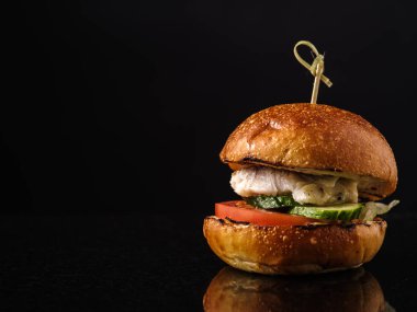 Karanlık bir arka plan üzerinde sebze taze balık burger.