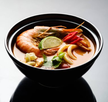 Siyah bir tabak içinde deniz ürünleri ile Tom Yam çorbası.