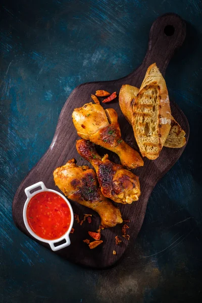 Jambes de poulet épicées frites sur le fond en bois avec la sauce — Photo