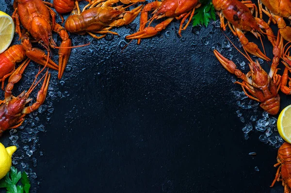 Fresh boiled crawfish with lemons and greens on a dark table wit — Stock Photo, Image