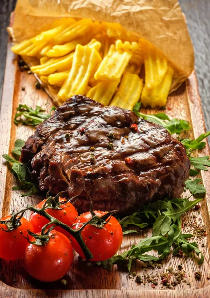 Bife grelhado saboroso suculento servido com tomate e francês — Fotografia de Stock