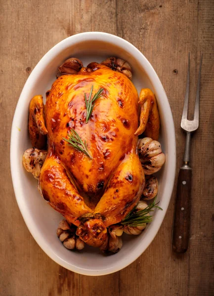 Gebratenes Huhn mit Knoblauch in einem weißen Teller auf einem Holztisch. — Stockfoto