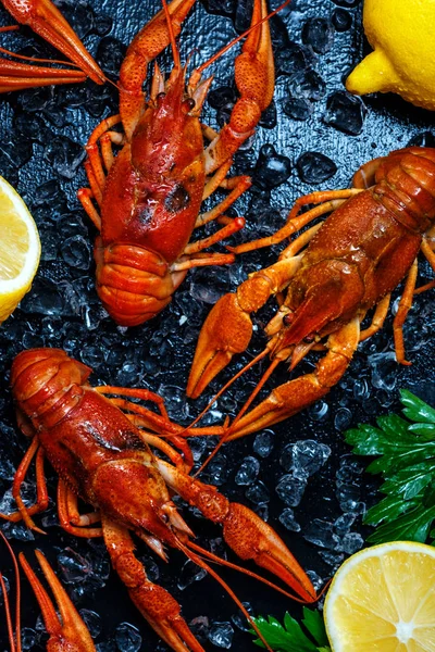 Fresh boiled crawfish with lemons and greens on a dark table wit — Stock Image Fresh boiled crawfish with lemons and greens on a dark table wit Stock Photo