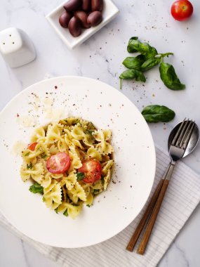 Parmesanlı Farfalle makarna, fesleğen ve kiraz domatesli. İtalyan mutfağı. Üst görünüm.