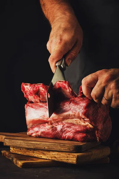 Male butcher cuts raw beef meat