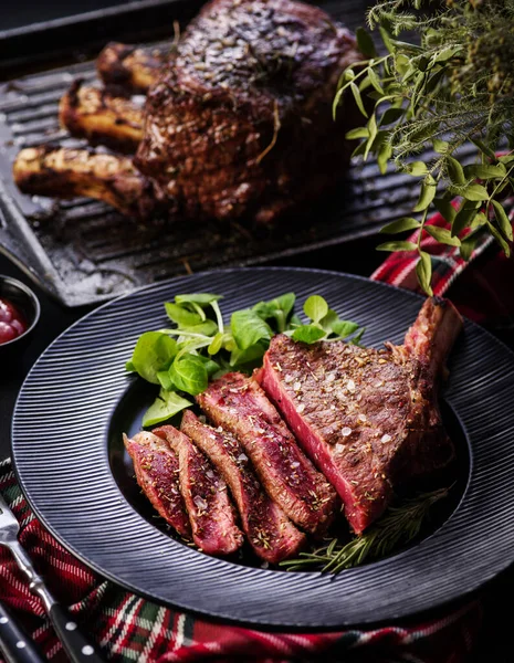 Steak on the bone. Rib eye. Tomahawk steak on the black plate with rosemary. Roasting - Rare. Entrecote.