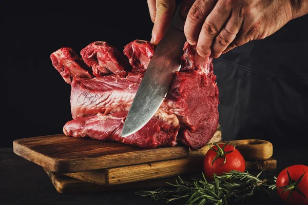 Male butcher cuts raw beef meat