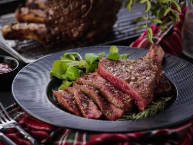 Steak on the bone. Rib eye. Tomahawk steak on the black plate with rosemary. Roasting - Rare. Entrecote. clipart