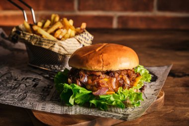 Tahta bir tahtanın üzerinde biftek ve karamelli soğan. Soğan ve sığır etli çizburger. Lezzetli Ev Yapımı Burger
