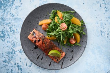 Roka salatası, vişneli domates ve portakallı sıcak füme somon. Sağlıklı beslenme. Üst görünüm.