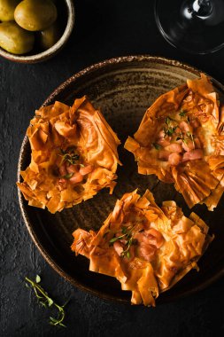 Füme somonlu kiş koyu bir arka planda ve bir bardak şarapla..