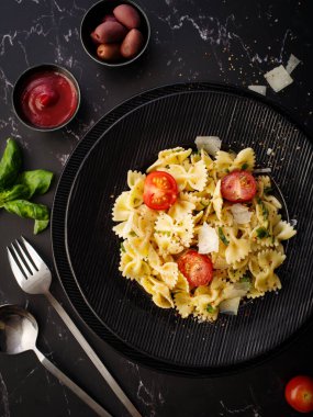 Parmesanlı Farfalle makarna, fesleğen ve kiraz domatesli. İtalyan mutfağı. Üst görünüm.