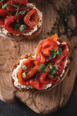 Yumuşak peynirli sandviç ve ahşap tahtada fırında kırmızı dolma biber. İtalyan bruschetta antipasti.