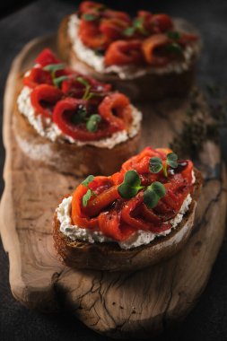 Yumuşak peynirli sandviç ve ahşap tahtada fırında kırmızı dolma biber. İtalyan bruschetta antipasti.