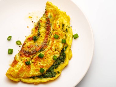 Ispanaklı omlet, yeşil soğan ve beyaz tabakta vişneli domates.