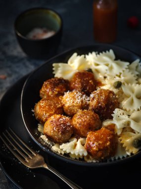 Domates soslu tavuk köfteli Farfalle makarna, koyu arkaplanda..