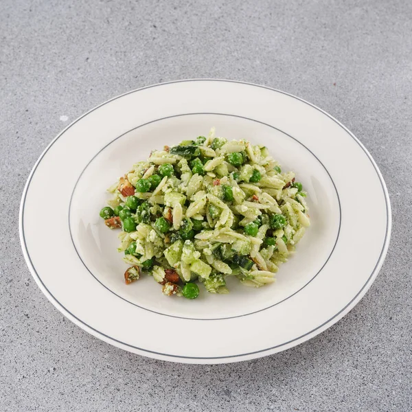 白い皿の上にエンドウ豆とナッツのオルゾパスタ — ストック写真