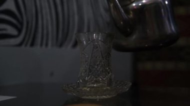 Çay bardağına sıcak çay döküldü.